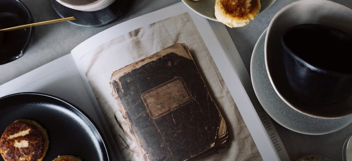 A rustic breakfast arrangement with pastries, tea, and a vintage book in a cozy still life composition.