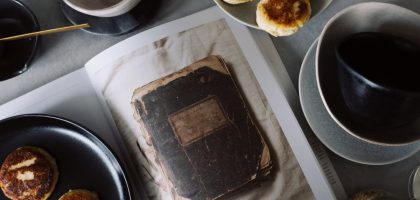 A rustic breakfast arrangement with pastries, tea, and a vintage book in a cozy still life composition.