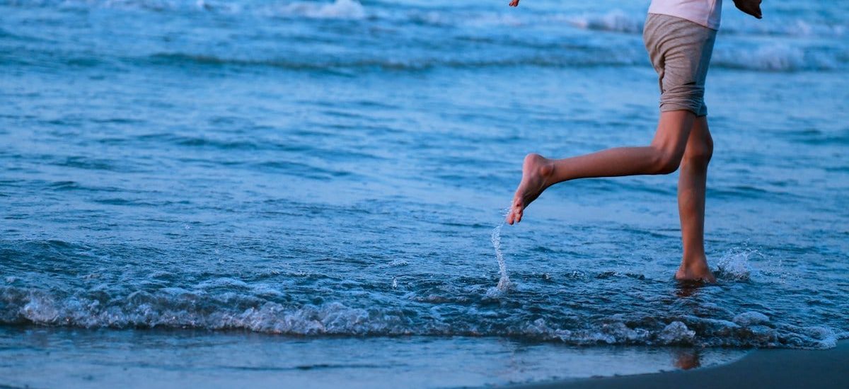a woman is running in the water at the beach