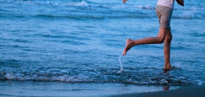a woman is running in the water at the beach