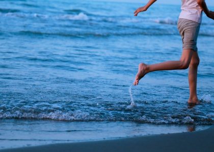 a woman is running in the water at the beach