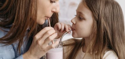 A mother and daughter sharing a strawberry milkshake indoors, depicting love and bonding.